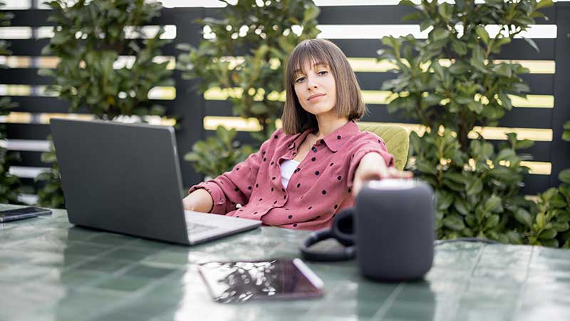 Rapariga no portátil com coluna inteligente